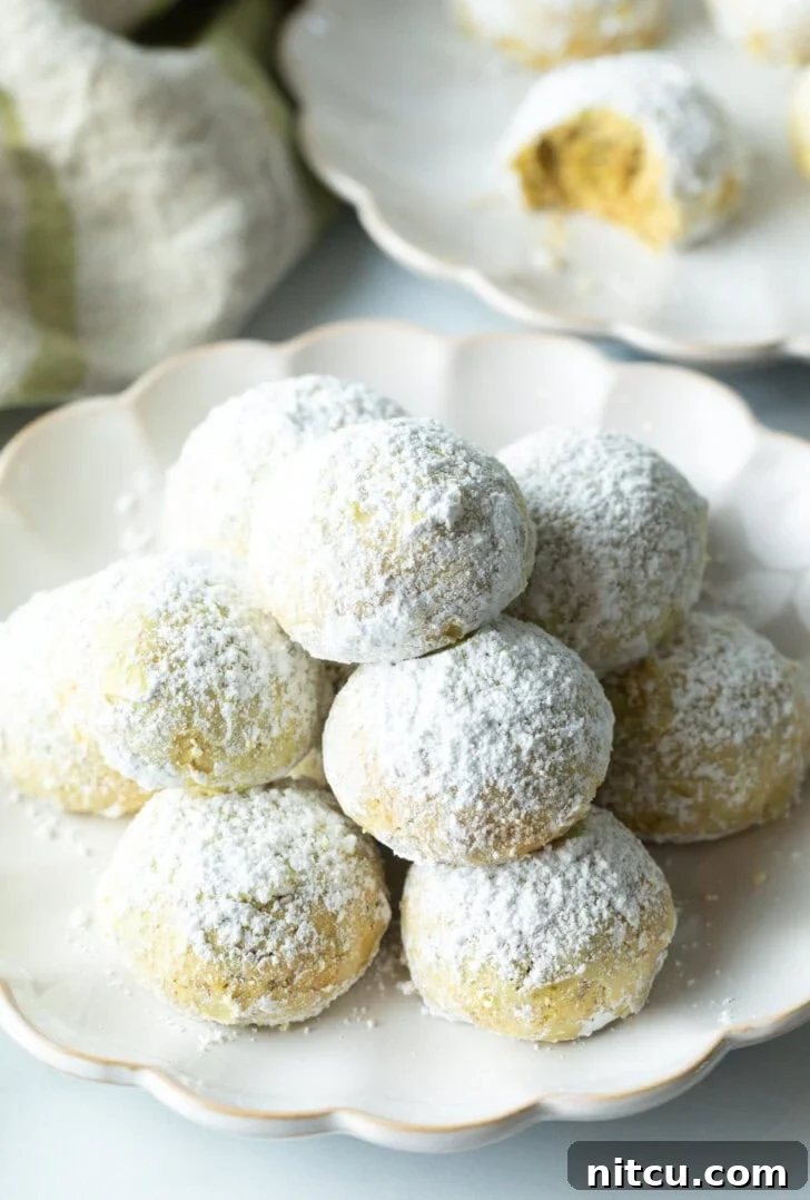 Pyramid stacks of almond and pistachio Italian wedding cookies dusted with powdered sugar, reminiscent of classic Russian Tea Cakes.