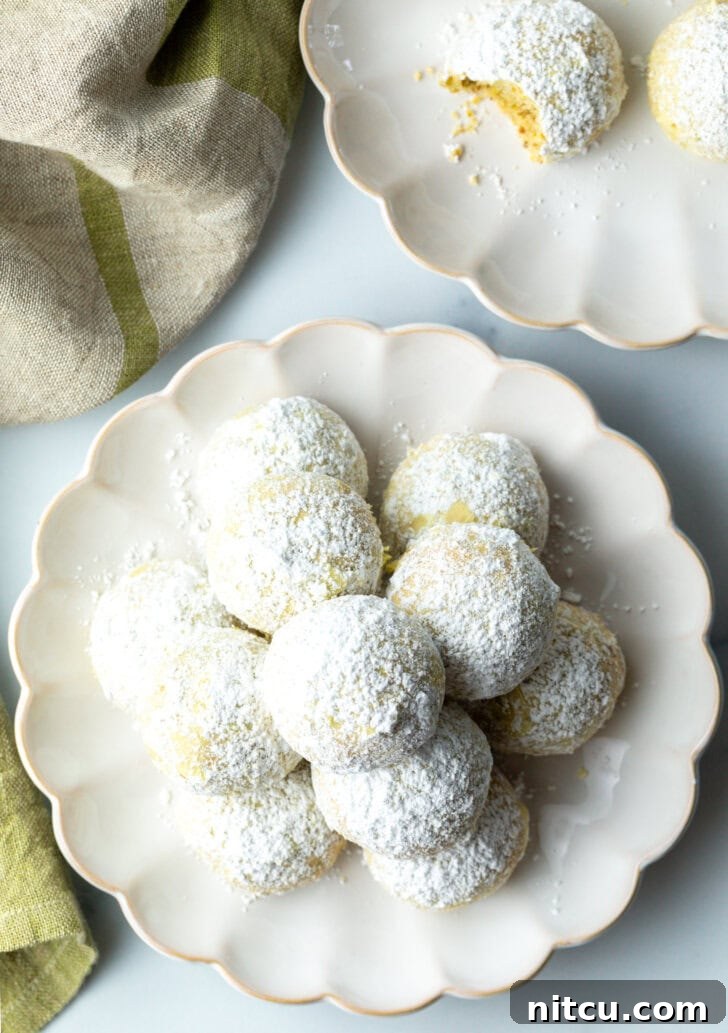 Top down view of pyramid stacks of almond and pistachio Italian wedding cookies, also known as Mexican Wedding Cookies or Russian Tea Cakes, generously dusted with powdered sugar.