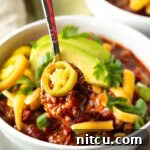 A bowl of venison chili with various toppings, representing the final dish.