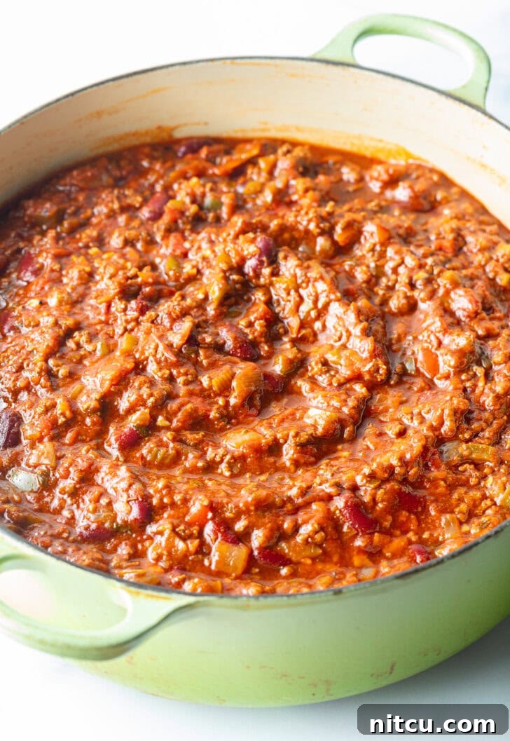 A hearty venison chili simmering gently in a large cooking pot, ready to be served.