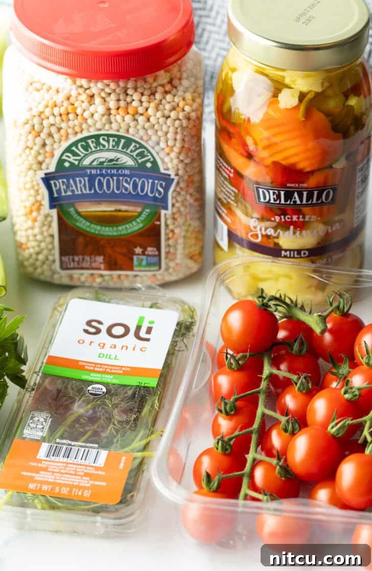 Recipe ingredients in individual containers: Pearl couscous, giardiniera pickled vegetables, on the vine cherry tomatoes, and fresh dill, showcasing freshness.