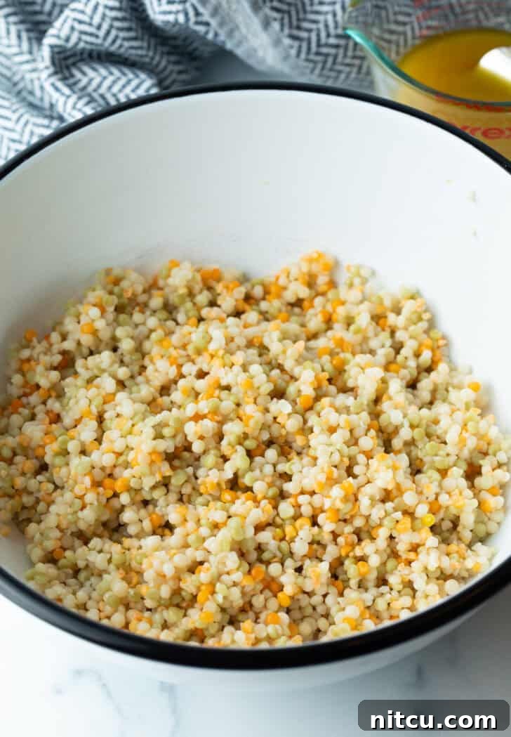 Cooked and cooled couscous in a large mixing bowl, ready for the other ingredients.