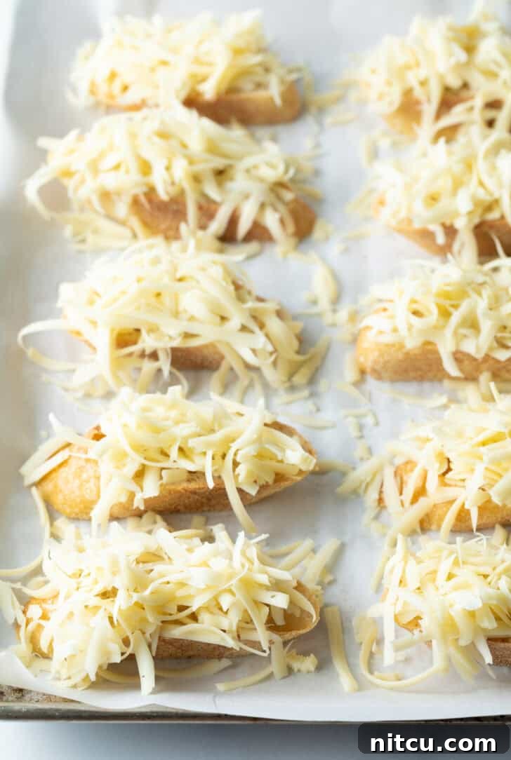 Bistro Onion Comfort 9 8 slices of baguette topped with shredded cheese, ready for broiling.