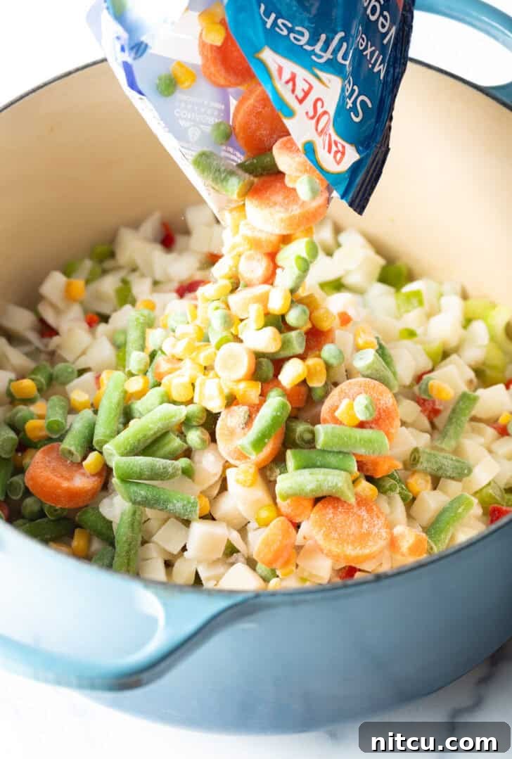 Velvety Garden Soup 7 Pouring a mix of frozen corn, green beans, carrots, and peas into a large cooking pot.