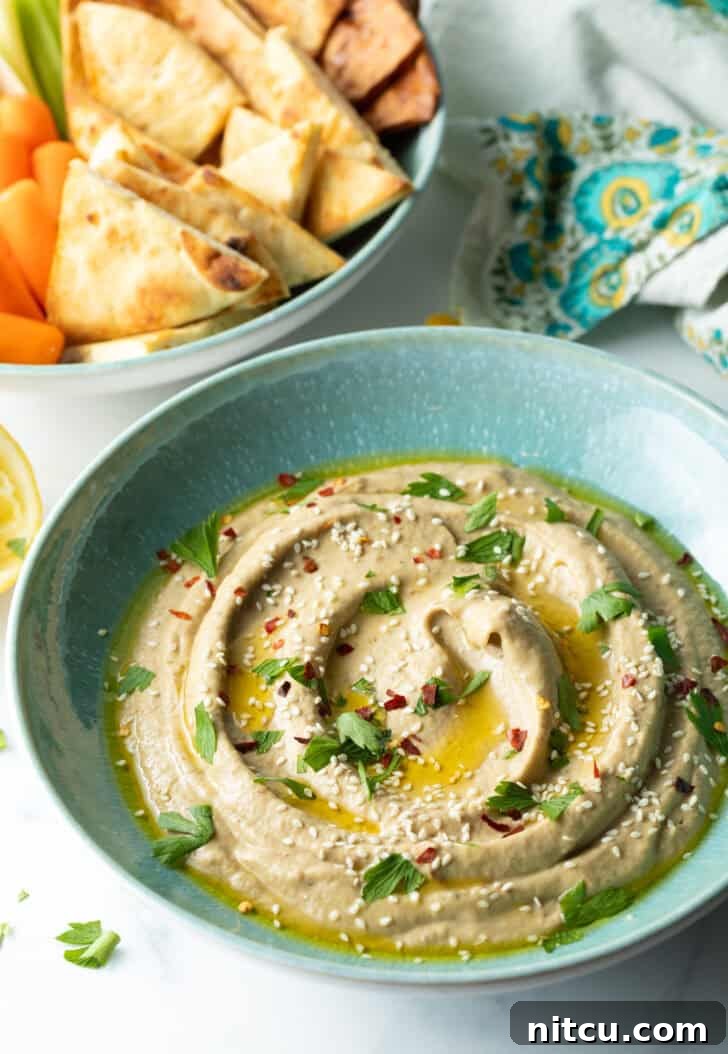 Light blue bowl of baba ganoush, garnished with fresh herbs and a drizzle of olive oil, ready to be served.
