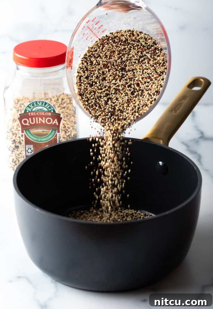Perfectly Fluffy Quinoa 5 Pouring soaked quinoa from a measuring container into a large black saucepot.
