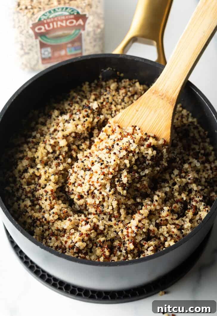 Perfectly Fluffy Quinoa 8 Stirring fluffy quinoa in a large black skillet with a wood spatula.