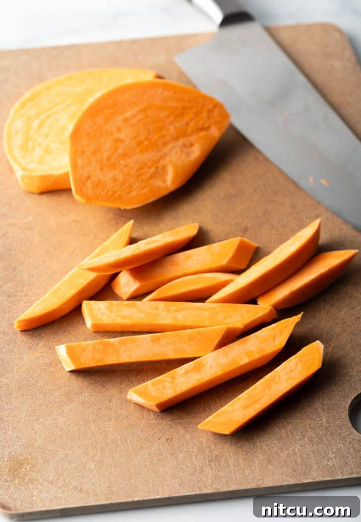 Crispy Air Fryer Sweet Potato Fries 5 Slicing fresh raw sweet potatoes with a large knife.