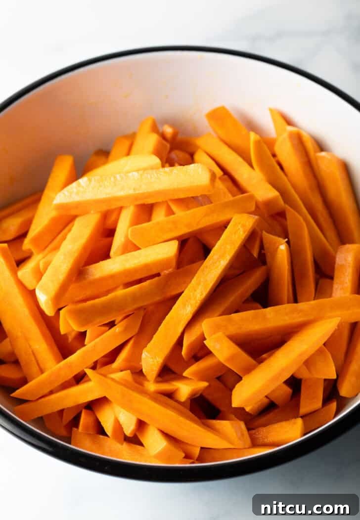 Crispy Air Fryer Sweet Potato Fries 6 Slices of raw sweet potato in a large white bowl.
