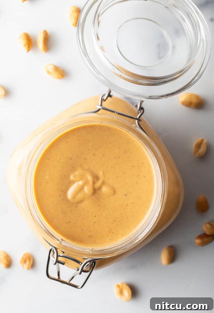 Whip Up Your Own Peanut Butter 4 Top down view of a glass container filled with freshly made, golden-brown homemade peanut butter, ready for storage.