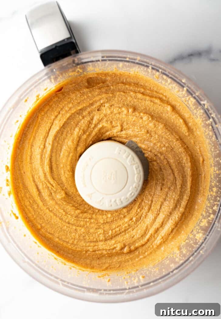 Whip Up Your Own Peanut Butter 9 Peanuts continuing to blend, becoming slightly creamy with small chunky pieces still visible.