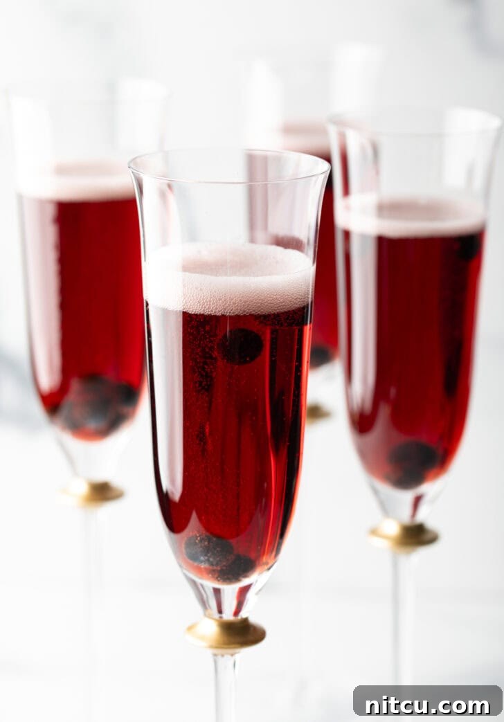 Regal Berry Fizz 2 Four fluted glasses with deep red Kir Royale cocktail drinks, elegantly presented for a celebration.
