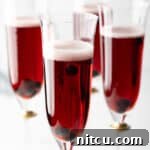 Four fluted glasses with deep red Kir Royale cocktail drinks, a visual representation of the final recipe.