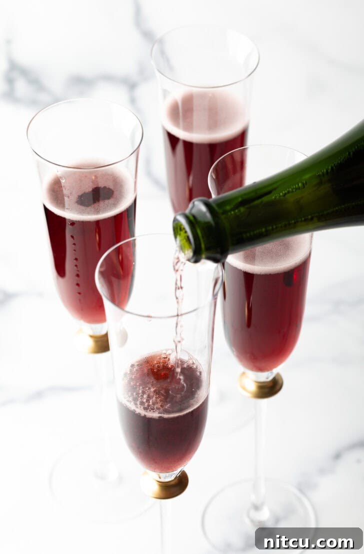 Regal Berry Fizz 7 Chilled champagne being poured over the crème de cassis in a fluted glass.