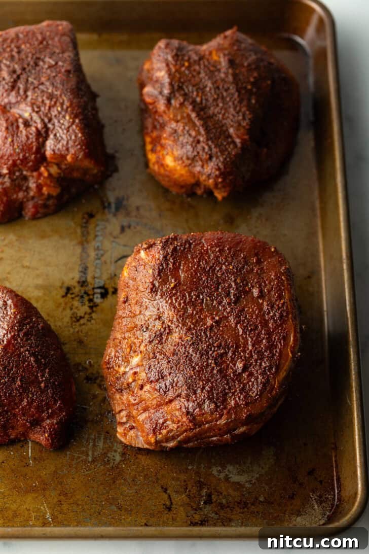 Achieve Steakhouse Quality with Reverse Searing 5 Four baked filets on a baking sheet.