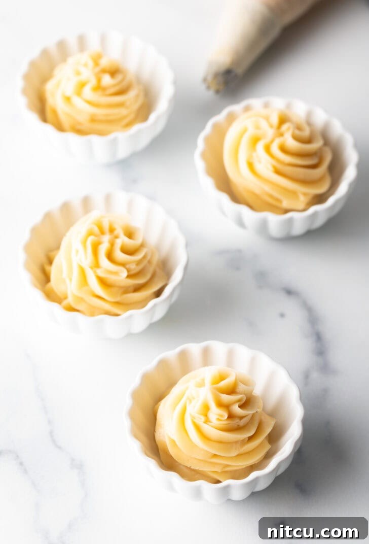 A collection of small white ramekins, each perfectly filled with a decorative swirl of piped whipped honey butter, ready for individual servings.