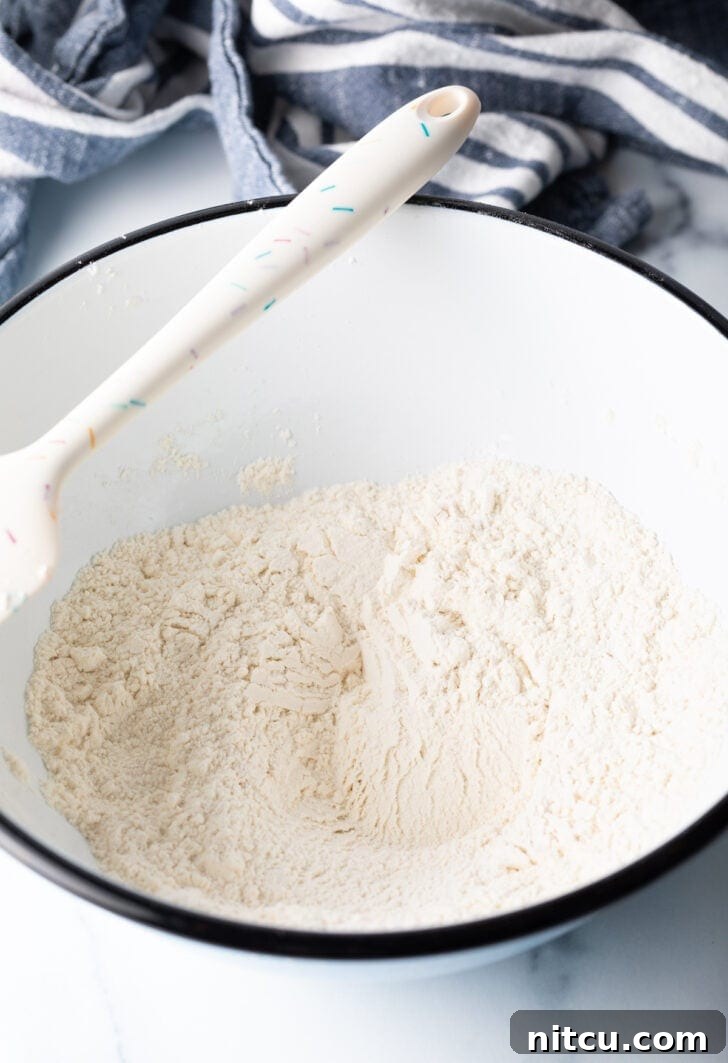 Pillowy Buttermilk Drop Biscuits 6 Flour and ingredients in a white bowl, with a white spatula.