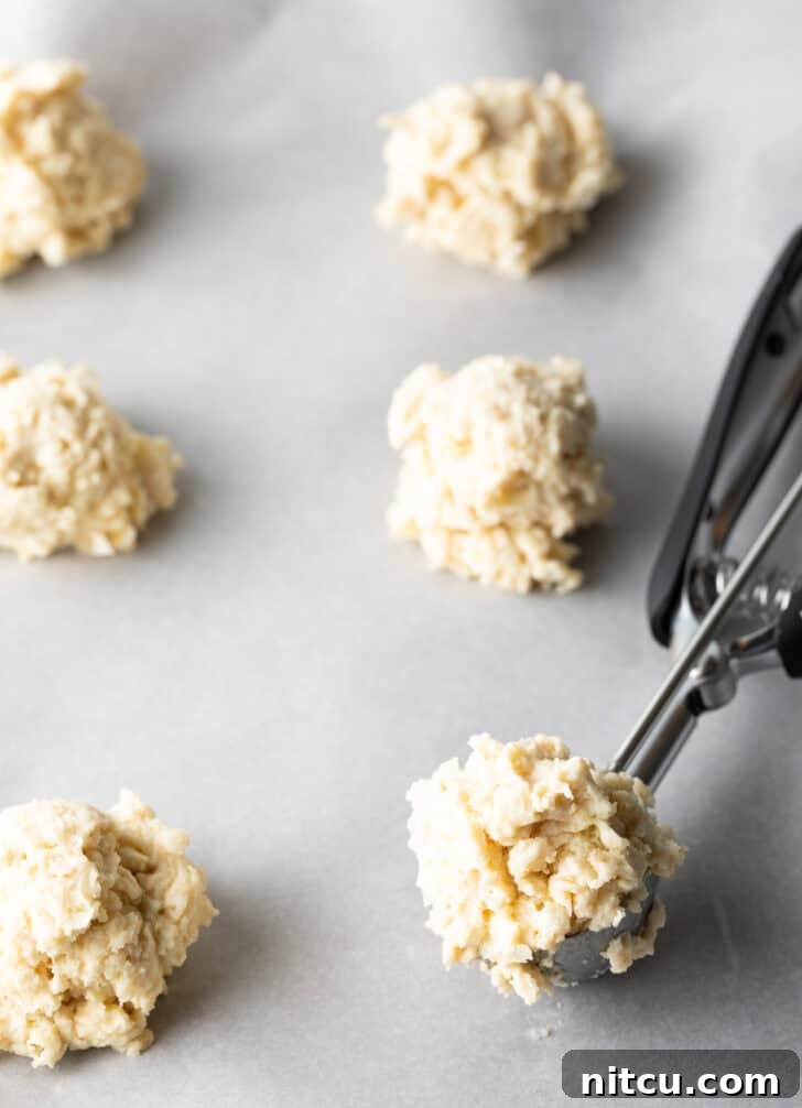 Pillowy Buttermilk Drop Biscuits 9 Using a metal cookie scoop to portion biscuit dough onto a baking sheet.