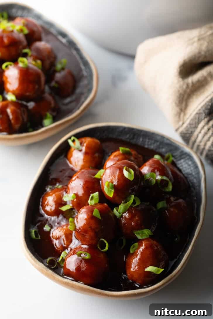 Sweet & Smoky Slow Cooker Meatballs 2 Bowl full of meatballs covered in barbecue sauce, topped with fresh chopped scallions.