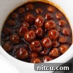 Sweet & Smoky Slow Cooker Meatballs 11 White slow cooker filled with meatballs in bbq sauce.