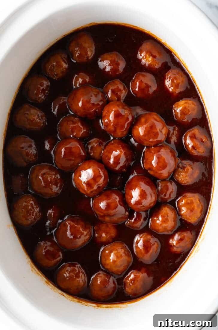 Sweet & Smoky Slow Cooker Meatballs 4 White slow cooker filled with meatballs in bbq sauce.