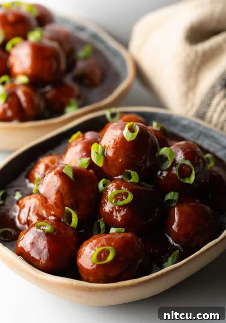 Sweet & Smoky Slow Cooker Meatballs 8 Bowl full of meatballs covered in barbecue sauce, topped with fresh chopped scallions.