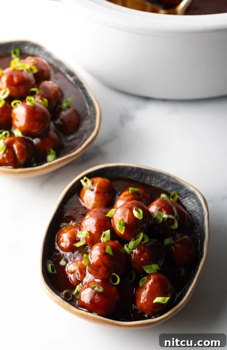 Sweet & Smoky Slow Cooker Meatballs 9 Bowl full of meatballs covered in barbecue sauce, topped with fresh chopped scallions.