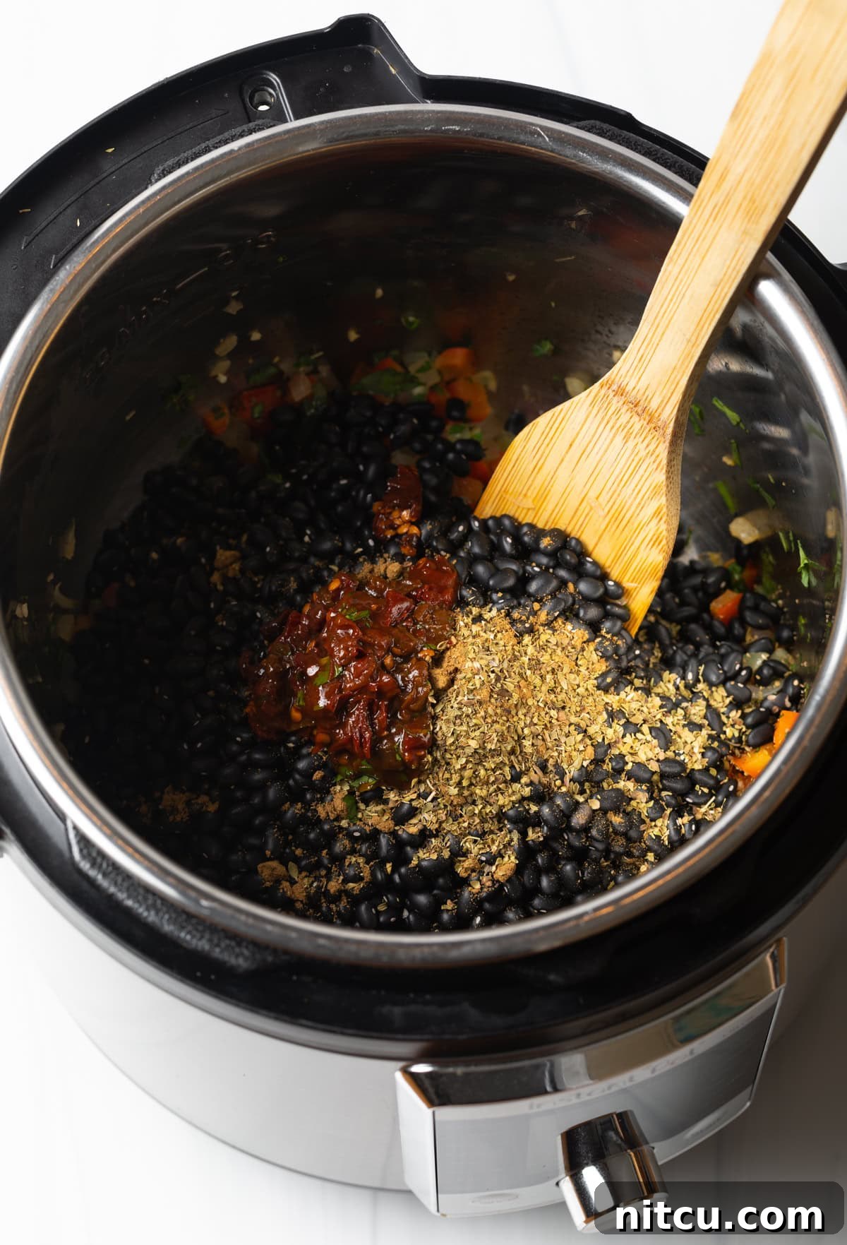 Hearty Black Bean Soup 6 Stirring garlic, chiles, and spices in with beans in an instant pot.