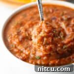 Charred Tomato Salsa 14 A metal spoon is showing a scoop of roasted salsa scooped from a white bowl.