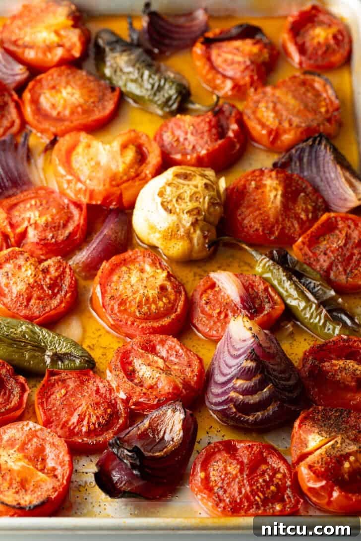 Charred Tomato Salsa 7 Top down view baking sheet brimming with roasted sliced tomatoes, jalapeno, and red onion chunks.