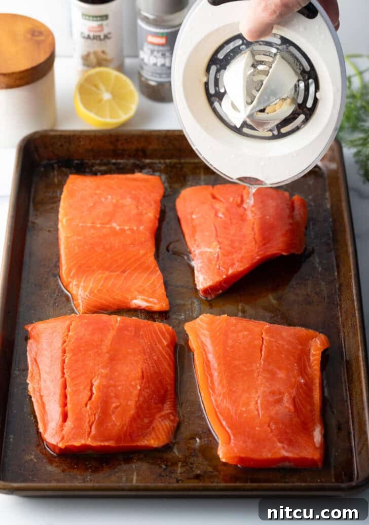 Perfect Oven-Baked Salmon 6 Raw salmon filets on a baking sheet, seasoned and ready for the oven.