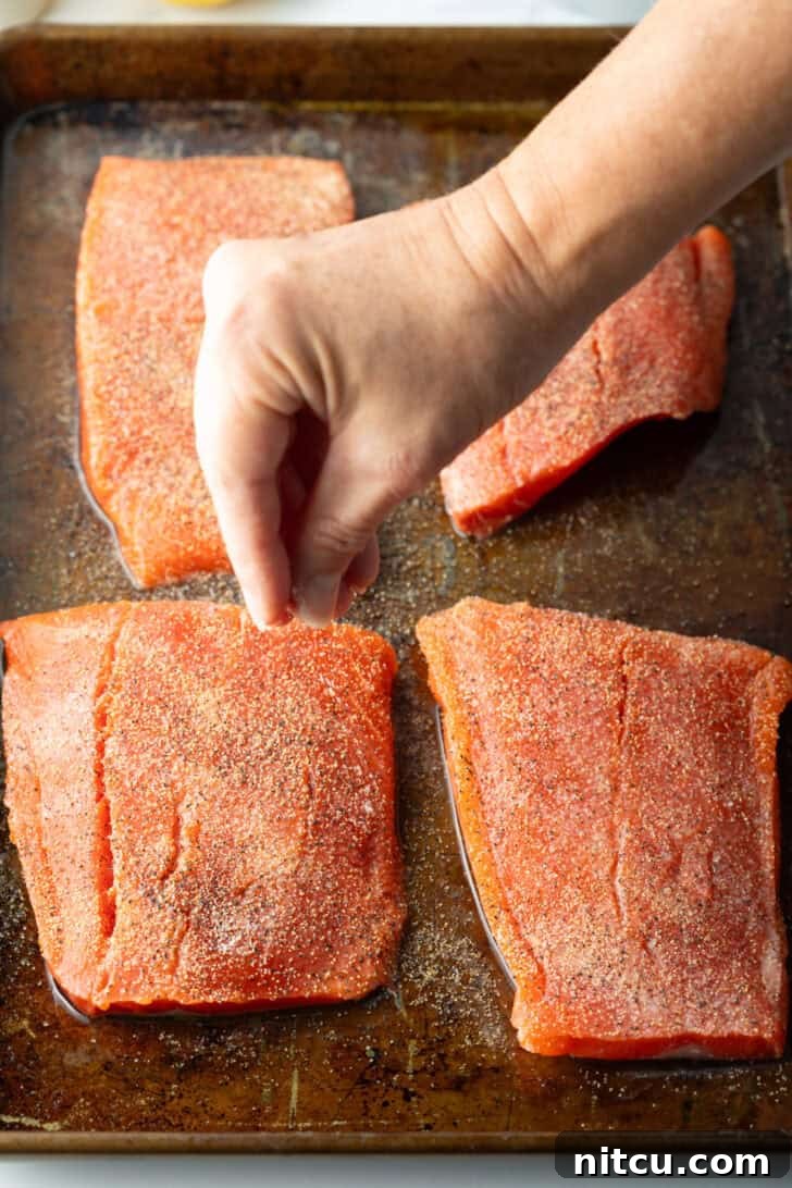 Perfect Oven-Baked Salmon 7 Close-up of raw salmon seasoned with spices on a baking sheet.