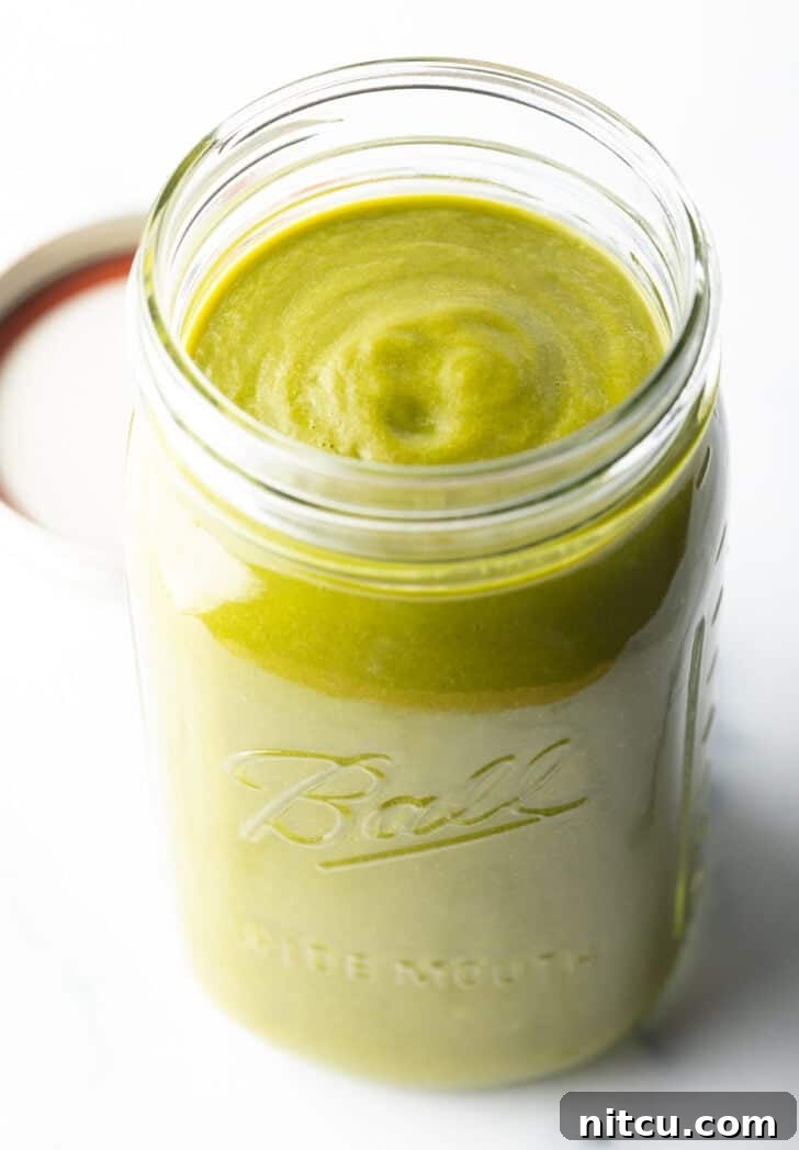 Large glass mason jar filled with bright green enchilada sauce, ready for use or storage.
