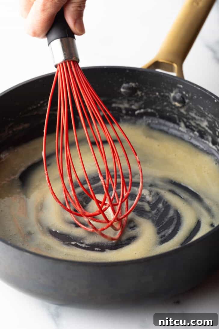 Authentic Red Enchilada Sauce 6 Red whisk stirring butter in a black skillet.
