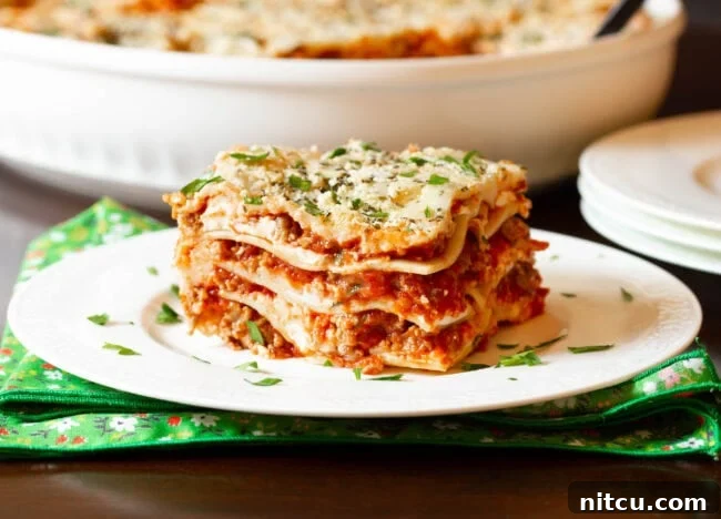 Homemade Lasagna with Cream Cheese | ASpicyPerspective.com #Lasagna #Pasta Easy sausage lasagna recipe with cream cheese, beautifully cut into squares on a white plate, ready to be served