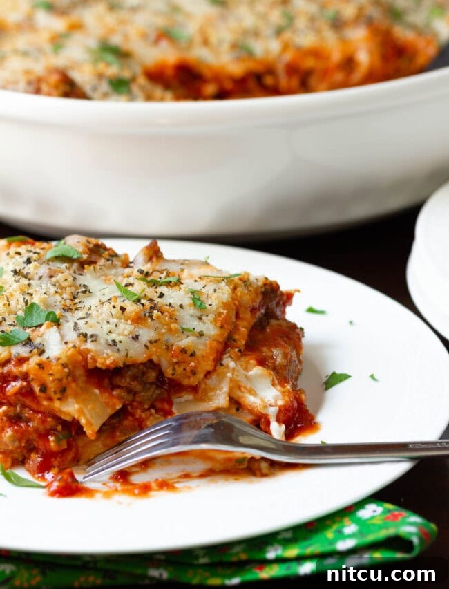 Sausage Lasagna | ASpicyPerspective.com #Lasagna #Pasta A delicious slice of Italian sausage lasagna on a plate with a bite taken out, showcasing its rich, layered interior.