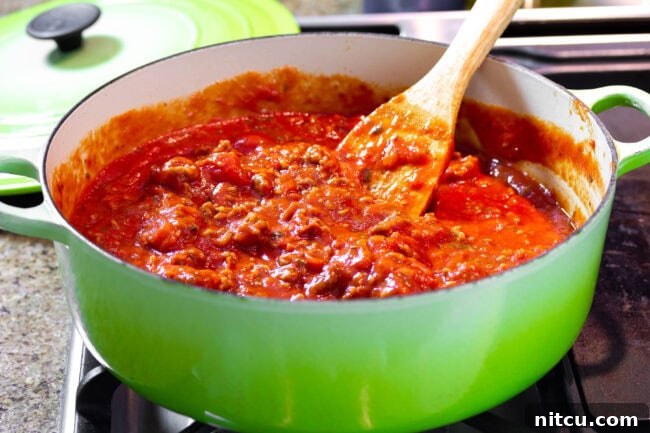 Meat Sauce | ASpicyPerspective.com #Lasagna #Pasta Close-up of rich Italian sausage and tomato sauce, simmering to perfection, a key component for cream cheese lasagna.