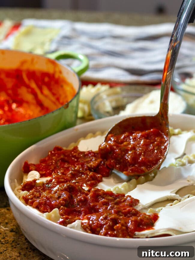 Rich Sausage Cream Cheese Lasagna 4 Adding a generous scoop of flavorful meat sauce to the layered cream cheese lasagna, building depth and richness.