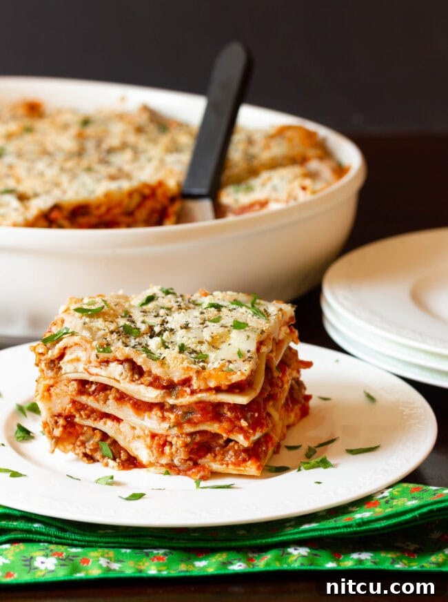 Sausage Lasagna with Cream Cheese | ASpicyPerspective.com #Lasagna #Pasta A generous slice of easy lasagna recipe with cream cheese, perfectly cut and served on a plate, showcasing its creamy layers.