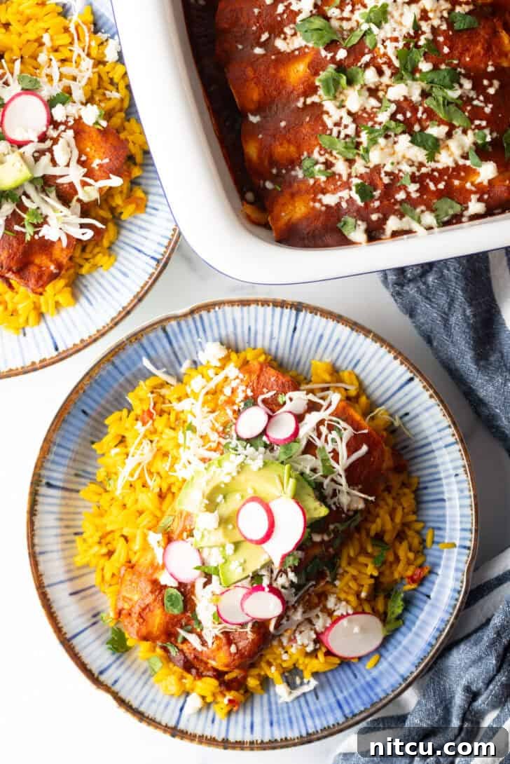 Grandma's Secret Enchiladas 4 Large plate with 2 authentic enchiladas covered in red sauce, on a pile of fluffy yellow rice and topped with fresh cabbage slaw, sliced radishes, and avocado.