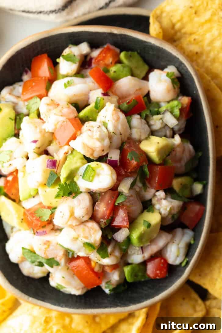 A top-down shot of a vibrant yellow bowl brimming with fresh shrimp ceviche, artfully surrounded by an assortment of golden tortilla chips, inviting guests to enjoy.
