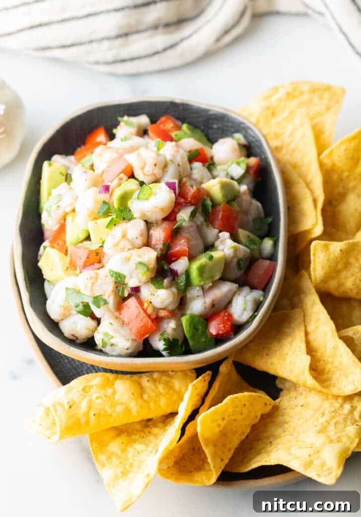 An inviting top-down view of a sunny yellow bowl of shrimp ceviche, artfully presented and surrounded by a generous spread of crispy tortilla chips, perfect for dipping.