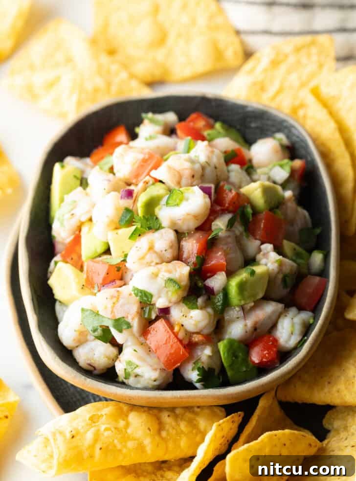 An overhead view of a vibrant yellow bowl brimming with fresh shrimp ceviche, surrounded by an array of golden tortilla chips, inviting a delicious scoop.