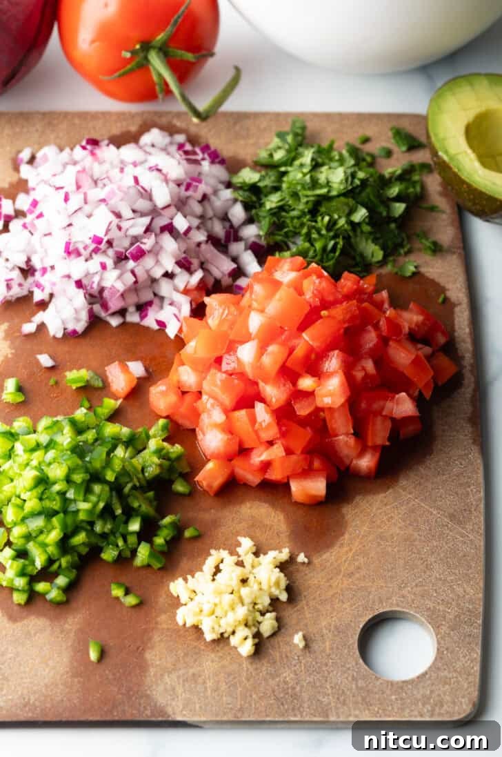 Recipe ingredients laid out: neat piles of chopped red peppers, vibrant green peppers, minced garlic, finely diced red onion, and fresh cilantro, all ready for the ceviche.