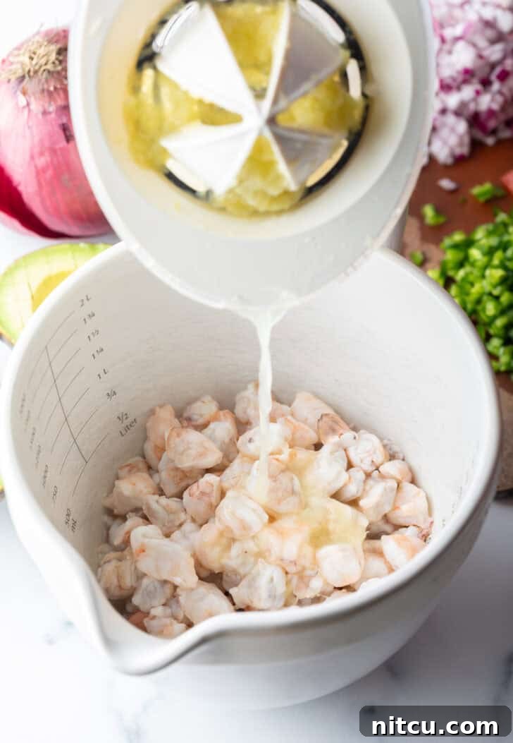 A hand expertly pouring freshly squeezed lime juice from a citrus juicer into a pristine white bowl containing raw shrimp, beginning the crucial marination process.