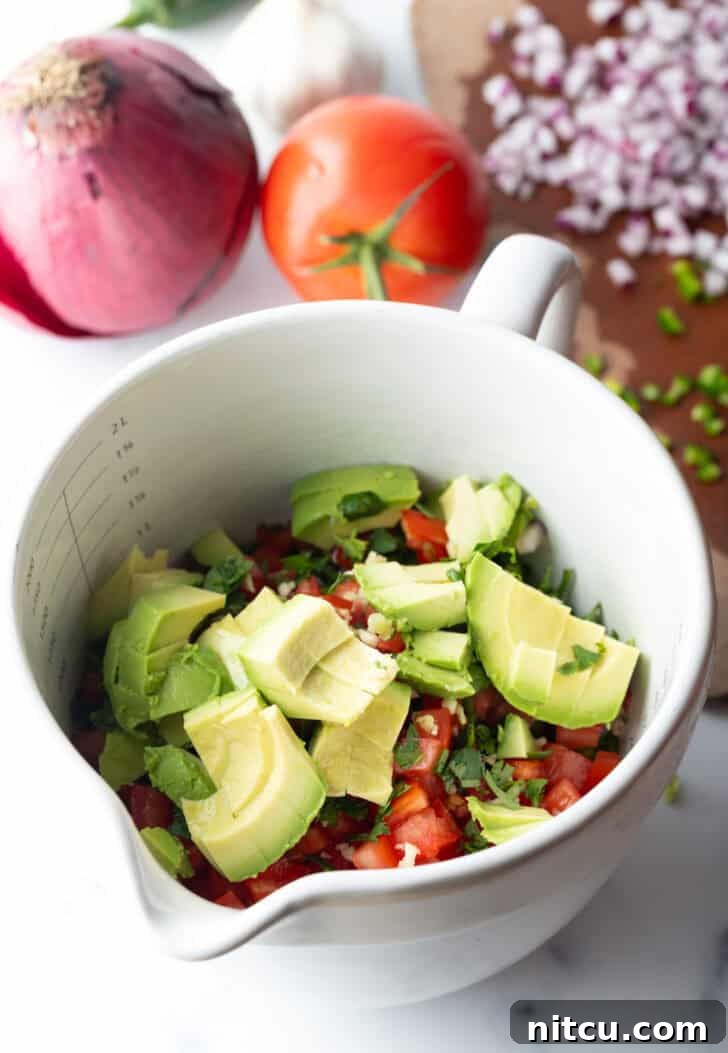 A creamy, perfectly ripe half avocado, cubed and ready to be added to the ceviche, resting in a pristine white bowl.