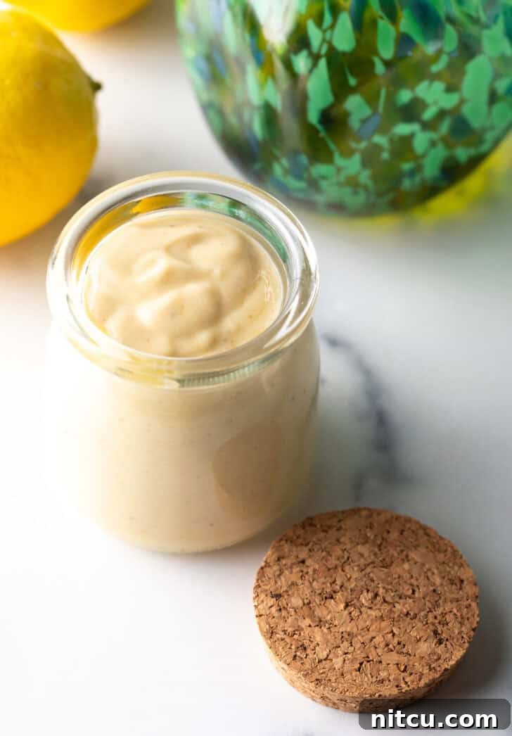Top-down view of a glass jar filled with rich, creamy, pale yellow tahini dressing, ready to be served.