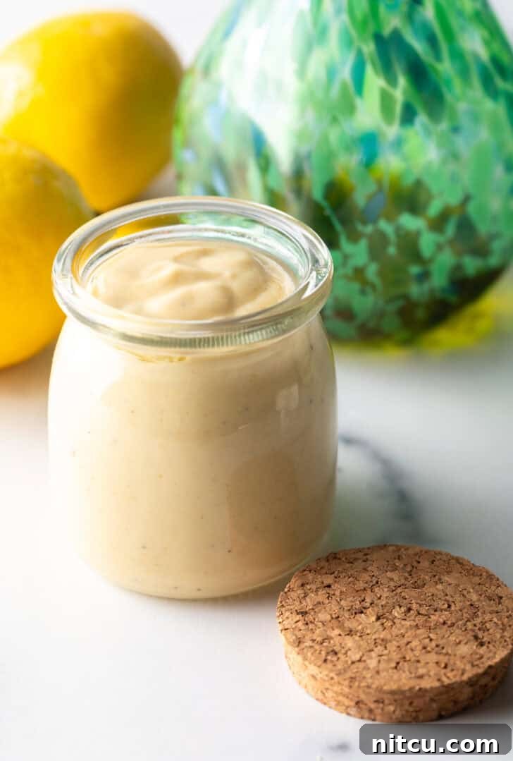 A clear glass jar filled with rich, creamy tahini dressing, showcasing its smooth texture.