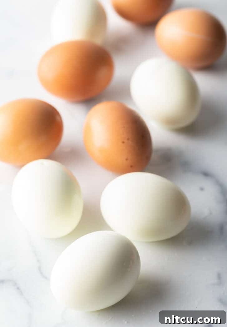 Top down view, four peeled hard boiled eggs and three brown unpeeled eggs.