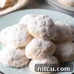 Light blue plate stacked with 3 layers of white Russian tea cakes covered in powdered sugar.